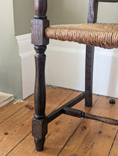 Load image into Gallery viewer, close up view of large oak ladder back rush seat on wooden floor