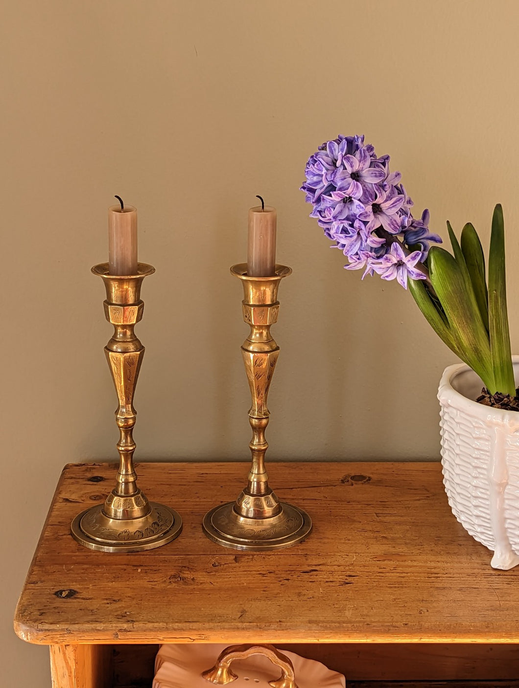 etched brass candlestick holders on shelf with flower in pot